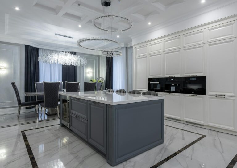 Sophisticated modern kitchen and dining area with marble flooring and stylish chandeliers.